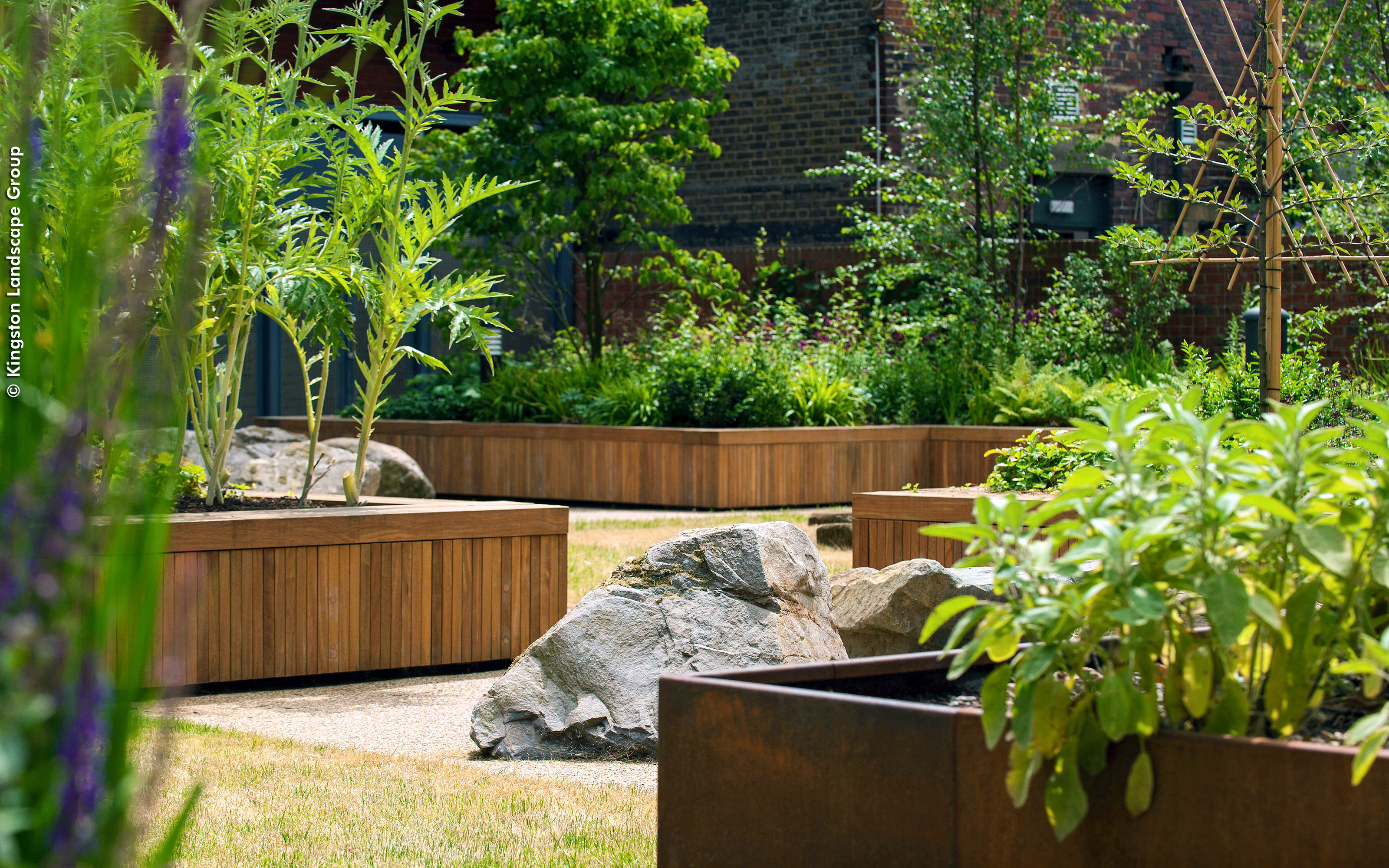Large rocks give the landscaped courtyard a natural appearance. Large rocks surrounded by planters with lush greenery